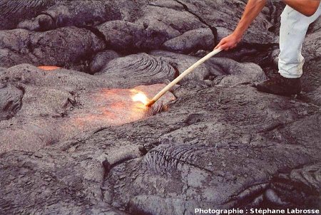 Touriste « touillant » de la lave cordée en formation à l'aide d'un bâton (qui s'enflamme), coulée du Pu'u O'o (Hawaii), été 2001