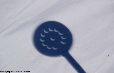 Ombre d'une écumoire sur un tissu blanc lors d'une éclipse partielle de Soleil (Égypte, 29 mars 2006)