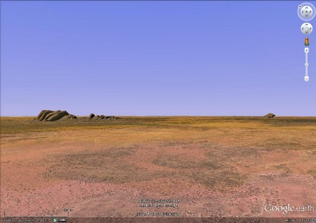 Vue rasante montrant les Taka Tjuta, à gauche, et Uluru, au fond à droite, distant de 30 km