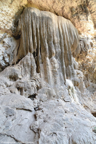 Vue d'ensemble de la structure interne d'une coulée stalagmitique, qui semble aussi un peu déviée vers la droite (vers la lumière), vallée du Wadi Darbat (Oman)