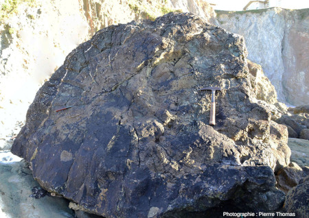 Moitié d'un très gros pillow lava (environ 2,5 m de diamètre) au pied d'une falaise (visible à l'arrière-plan) de laquelle il s'est éboulé, plage de Menakoz, Pays basque espagnol