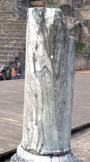 Vue d'ensemble d'une colonne du théâtre antique de Fourvière montrant des “plis” et deux fractures quasi verticales remplies de calcite (flèches) dont l'une (flèche rouge) traverse la colonne de bas en haut