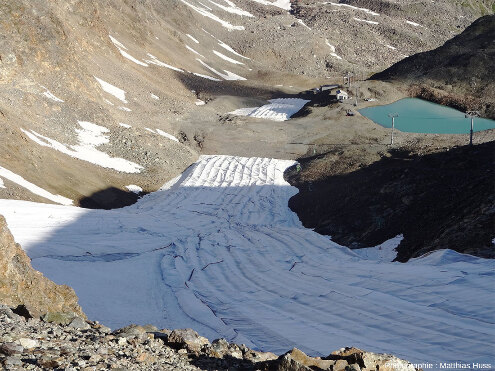 Vue depuis le sol sur des textiles blancs déposés sur une piste de ski afin d'en limiter la fonte et d'en prolonger l'utilisation de quelques semaines par an