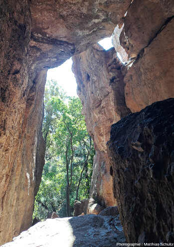 Entrée Est du Saint-Trou vue depuis l'intérieur, cavité formée par l'érosion, probablement en reprenant une zone fragilisée par un accident tectonique ou une diaclase, sur la face Nord-Est du rocher de Roquebrune-sur-Argens (Var)
